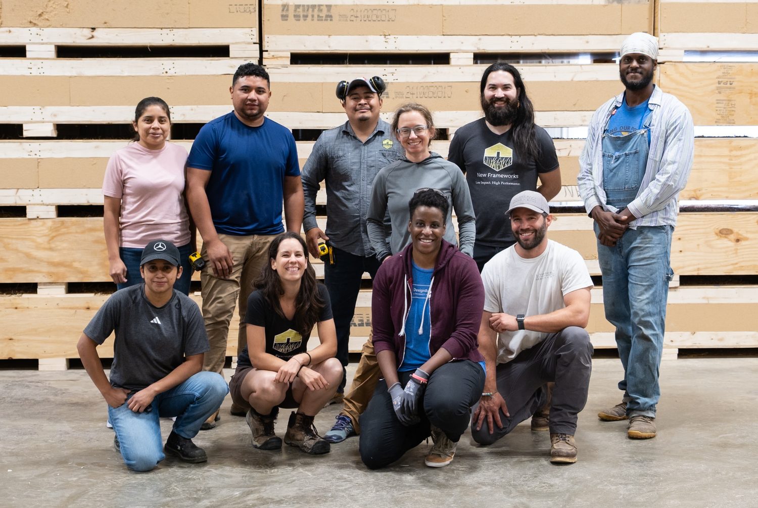 A Seed Program cohort of eleven people standing and kneeling together in a fabrication shop